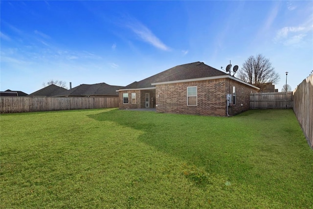 back of house with brick siding, a lawn, and a fenced backyard