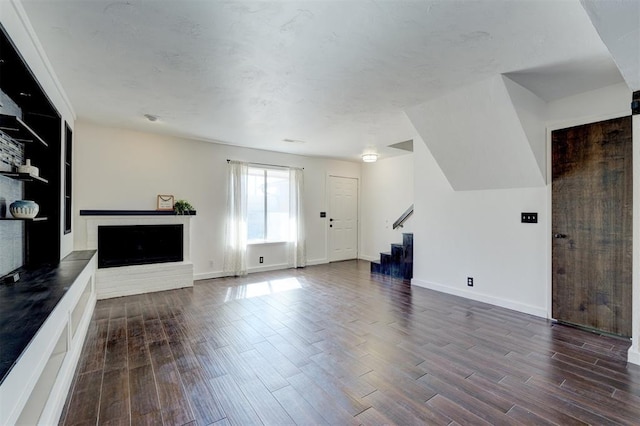 unfurnished living room with a brick fireplace and dark hardwood / wood-style floors