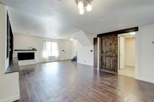 unfurnished living room featuring dark wood-type flooring and a barn door