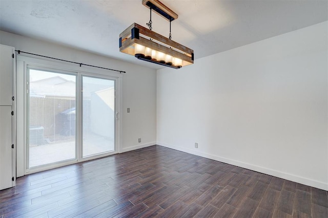 empty room featuring dark hardwood / wood-style flooring and a notable chandelier