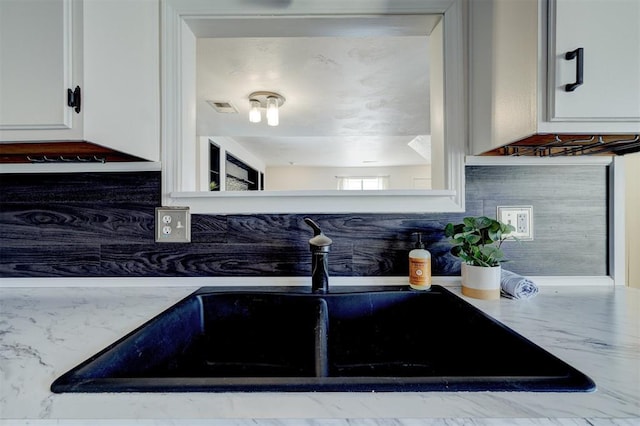 room details featuring white cabinetry, sink, and decorative backsplash