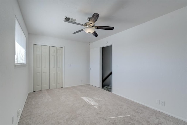 unfurnished bedroom featuring ceiling fan, a closet, and light carpet