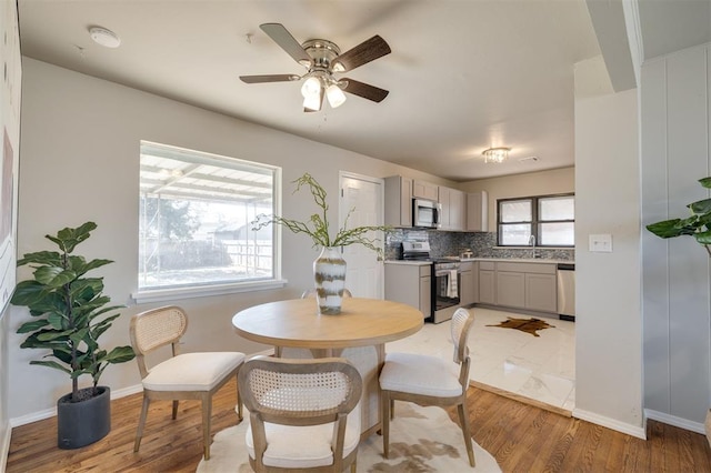 dining area with ceiling fan, sink, and light hardwood / wood-style flooring