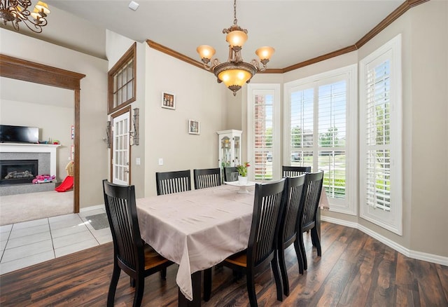 dining space with dark wood-type flooring, ornamental molding, and a chandelier