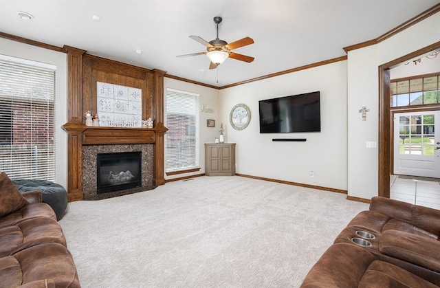 living room featuring a premium fireplace, ornamental molding, light carpet, and ceiling fan