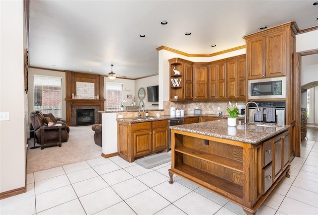 kitchen with tasteful backsplash, an island with sink, dark stone counters, kitchen peninsula, and stainless steel appliances