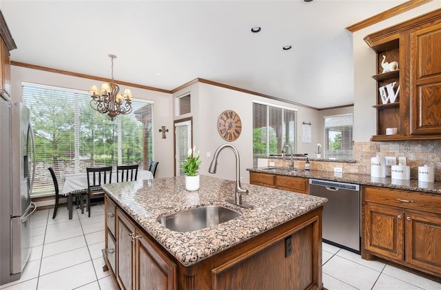 kitchen with light stone countertops, an island with sink, appliances with stainless steel finishes, and sink