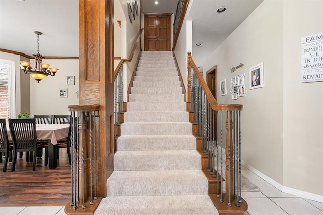 stairway with ornamental molding, tile patterned floors, and an inviting chandelier