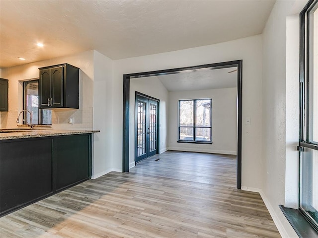 kitchen with french doors, light wood-type flooring, a sink, and baseboards