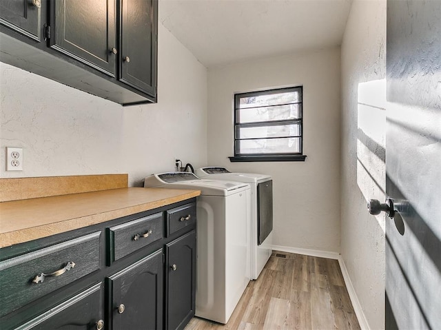 laundry area featuring cabinet space, light wood-style flooring, baseboards, and separate washer and dryer