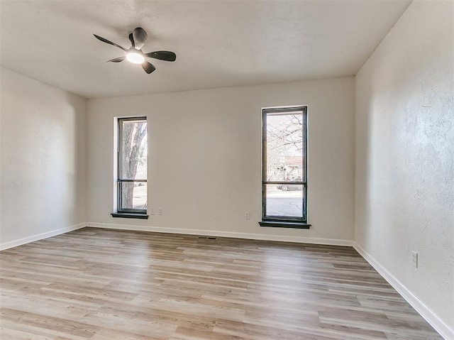 spare room with light wood finished floors, plenty of natural light, and baseboards