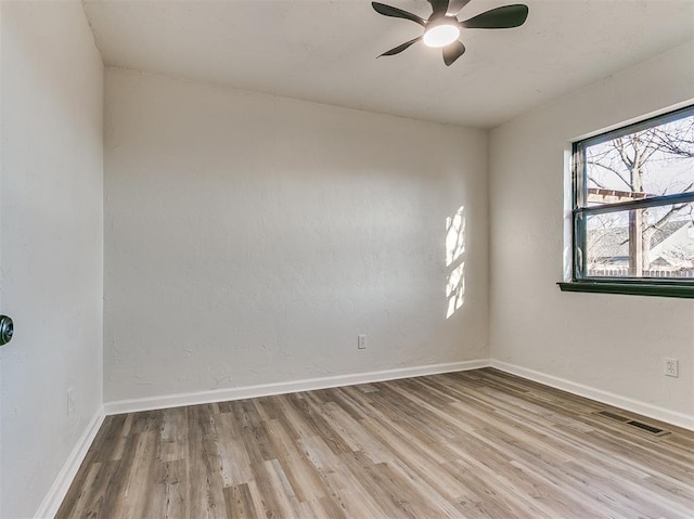 spare room featuring ceiling fan, wood finished floors, visible vents, and baseboards