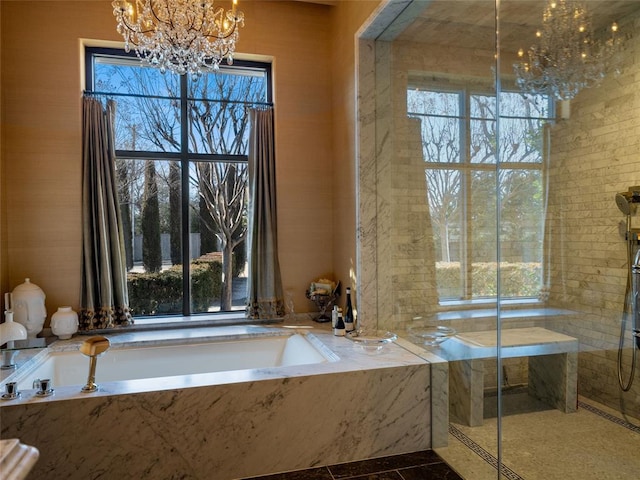 bathroom with an inviting chandelier, a healthy amount of sunlight, and tiled bath