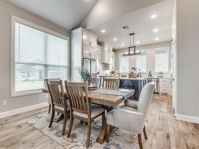 dining area featuring a healthy amount of sunlight, sink, and light wood-type flooring