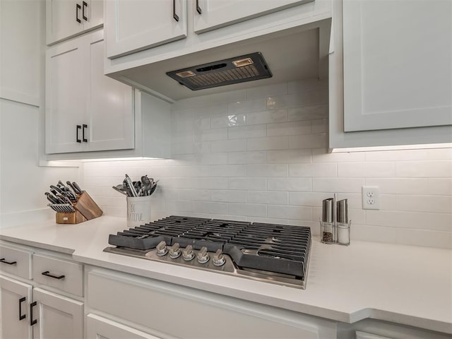 kitchen with stainless steel gas cooktop, wall chimney range hood, white cabinets, and decorative backsplash