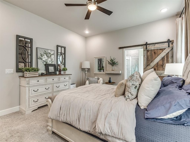 carpeted bedroom featuring ceiling fan and a barn door