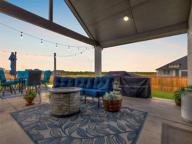 patio terrace at dusk featuring area for grilling and an outdoor living space with a fire pit