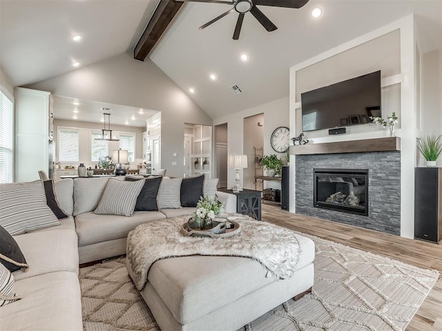 15417 Jasper Ln, Edmond, OK 73013 - living area with light wood-type flooring, visible vents, beamed ceiling, a ceiling fan, and a fireplace