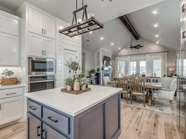 15417 Jasper Ln, Edmond, OK 73013 - kitchen featuring light wood finished floors, stainless steel appliances, open floor plan, vaulted ceiling with beams, and visible vents