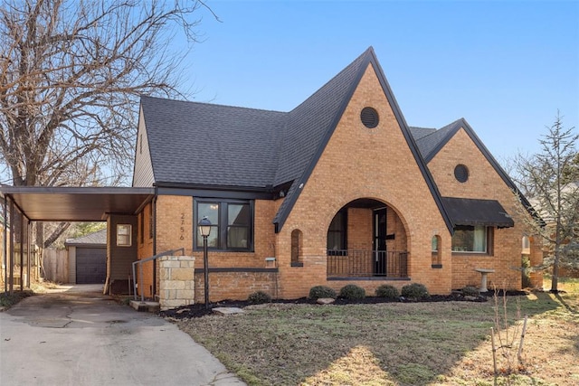 tudor-style house featuring a garage, a front lawn, a carport, and a porch