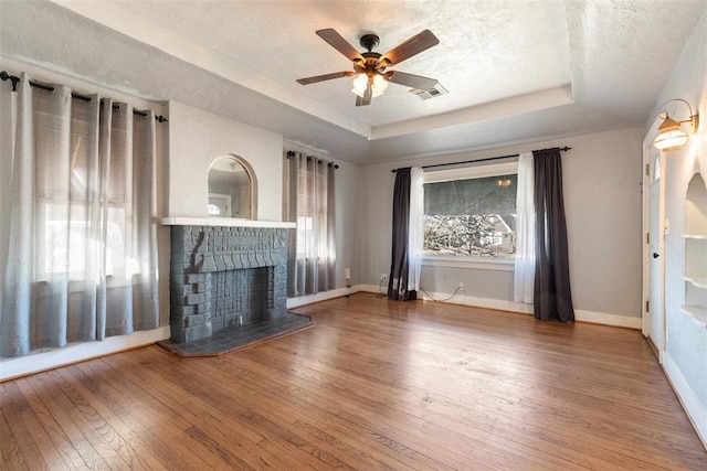 unfurnished living room featuring hardwood / wood-style flooring, ceiling fan, a raised ceiling, and a textured ceiling