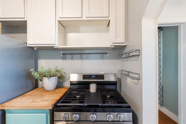 kitchen with white cabinetry, butcher block countertops, and stainless steel gas range oven