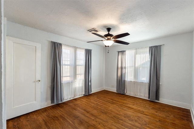 empty room with a textured ceiling, wood-type flooring, and ceiling fan