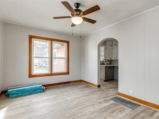 spare room with ceiling fan, sink, crown molding, and light wood-type flooring