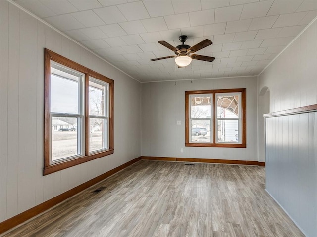 unfurnished room featuring light hardwood / wood-style flooring, crown molding, and plenty of natural light