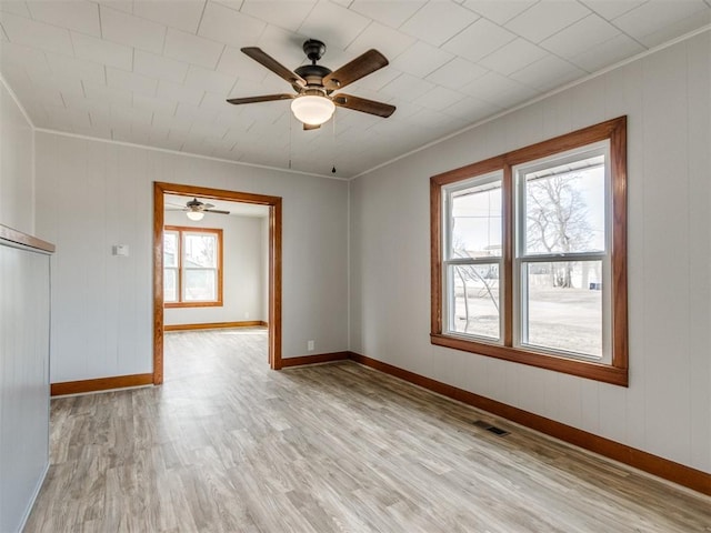 empty room featuring a healthy amount of sunlight, ornamental molding, and light hardwood / wood-style floors