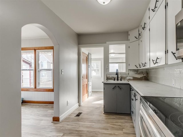kitchen with light wood-type flooring, sink, decorative backsplash, and white cabinets