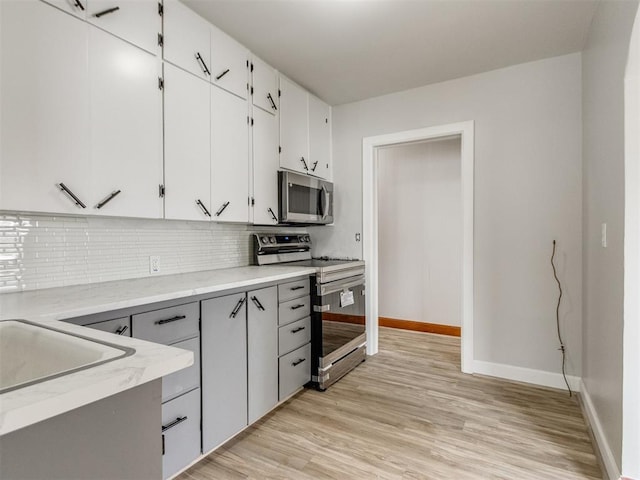 kitchen featuring tasteful backsplash, appliances with stainless steel finishes, light hardwood / wood-style floors, and white cabinets