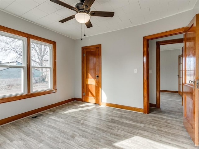 empty room with ceiling fan and light hardwood / wood-style flooring