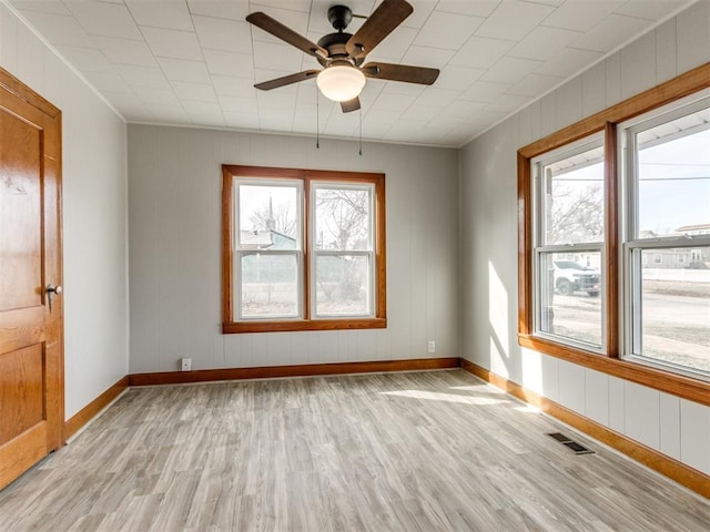 empty room featuring ceiling fan, a healthy amount of sunlight, and light wood-type flooring