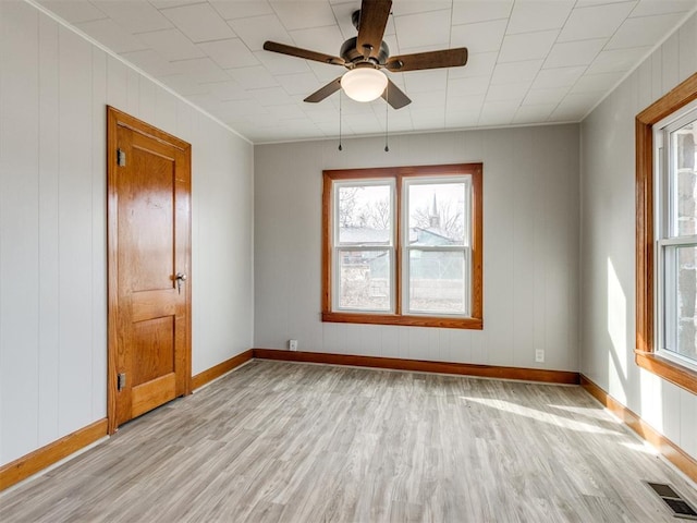 empty room featuring ceiling fan, crown molding, and light wood-type flooring