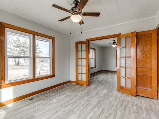 empty room featuring french doors, ceiling fan, ornamental molding, and light hardwood / wood-style floors