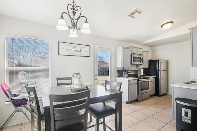 kitchen featuring gray cabinetry, decorative light fixtures, and stainless steel appliances