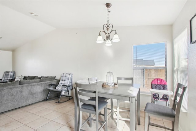 tiled dining space with lofted ceiling and a chandelier