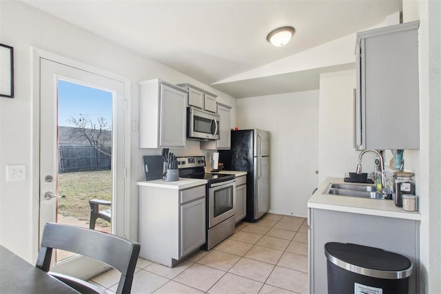 kitchen featuring gray cabinetry, sink, stainless steel appliances, and lofted ceiling