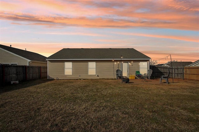 back house at dusk featuring a yard and a patio area