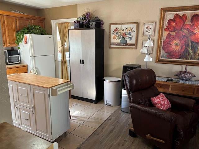 kitchen featuring wood counters, light tile patterned flooring, and freestanding refrigerator