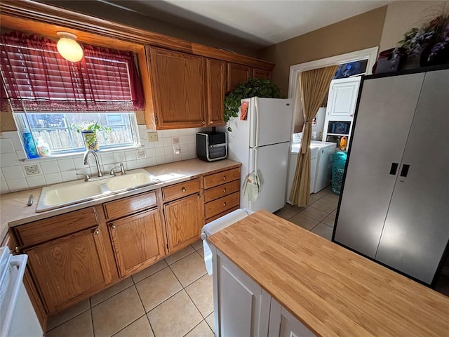 kitchen featuring freestanding refrigerator, a sink, decorative backsplash, and light tile patterned floors