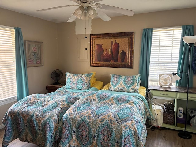 bedroom with ceiling fan, electric panel, and wood finished floors