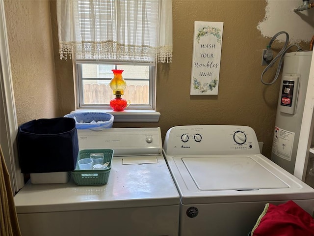 clothes washing area featuring water heater, laundry area, independent washer and dryer, and a textured wall