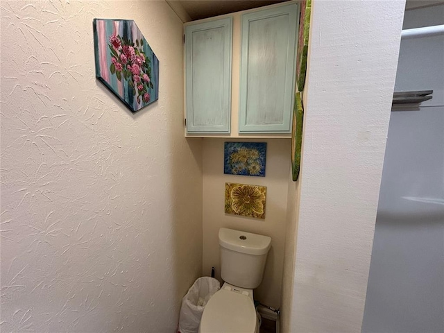 bathroom featuring a textured wall and toilet