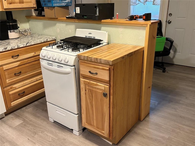 kitchen with light wood-style flooring, butcher block countertops, black microwave, and gas range gas stove