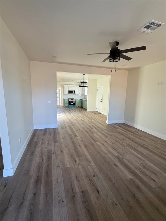 unfurnished living room featuring dark hardwood / wood-style floors and ceiling fan