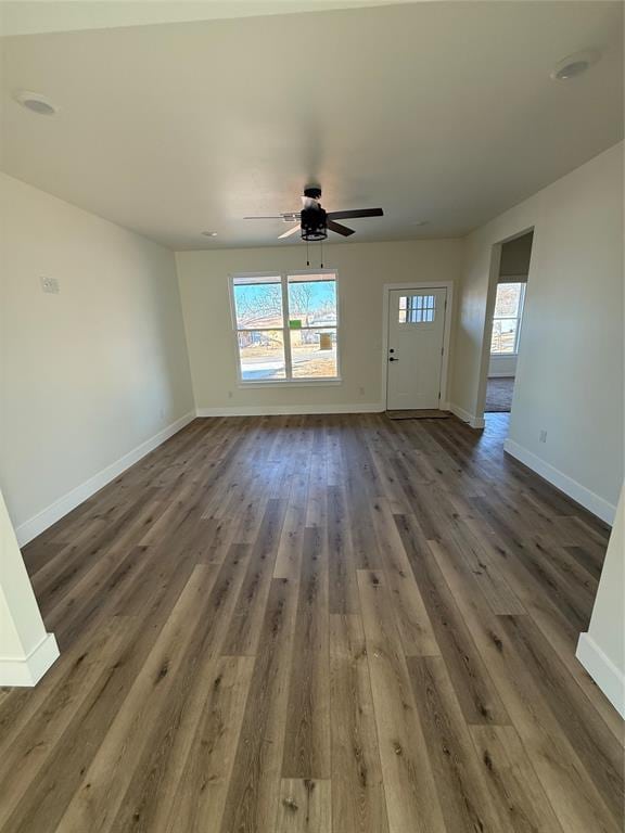 unfurnished living room featuring ceiling fan, a wealth of natural light, and dark hardwood / wood-style flooring