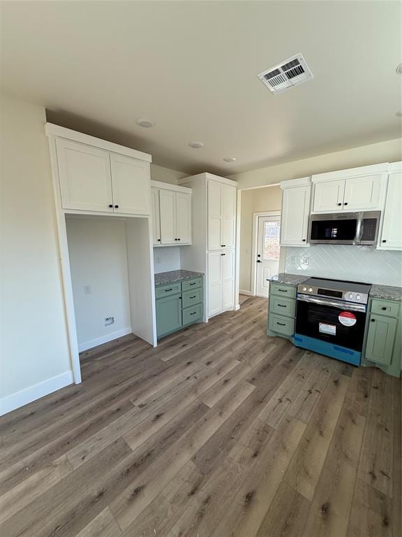 kitchen with green cabinetry, light wood-type flooring, stainless steel appliances, decorative backsplash, and white cabinets