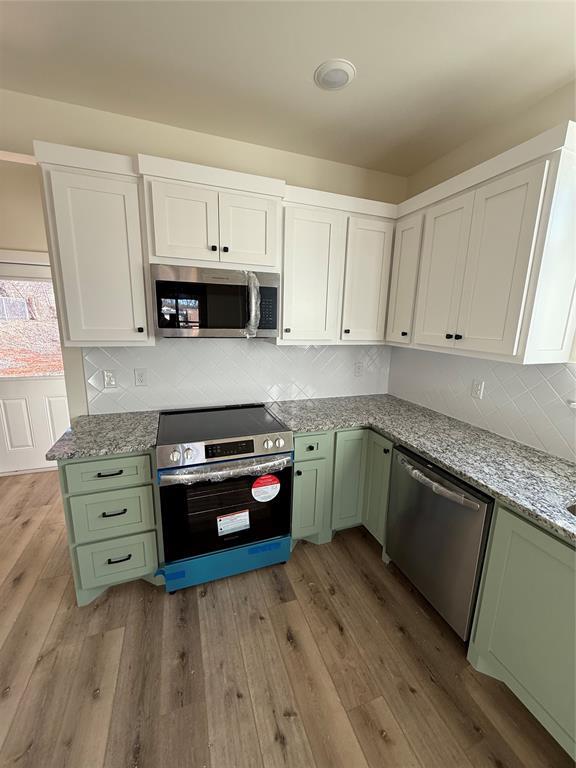 kitchen featuring white cabinetry, light hardwood / wood-style flooring, stainless steel appliances, and green cabinets